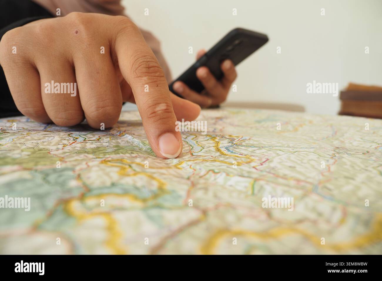 Person studies a map while using a smartphone for directions Stock Photo