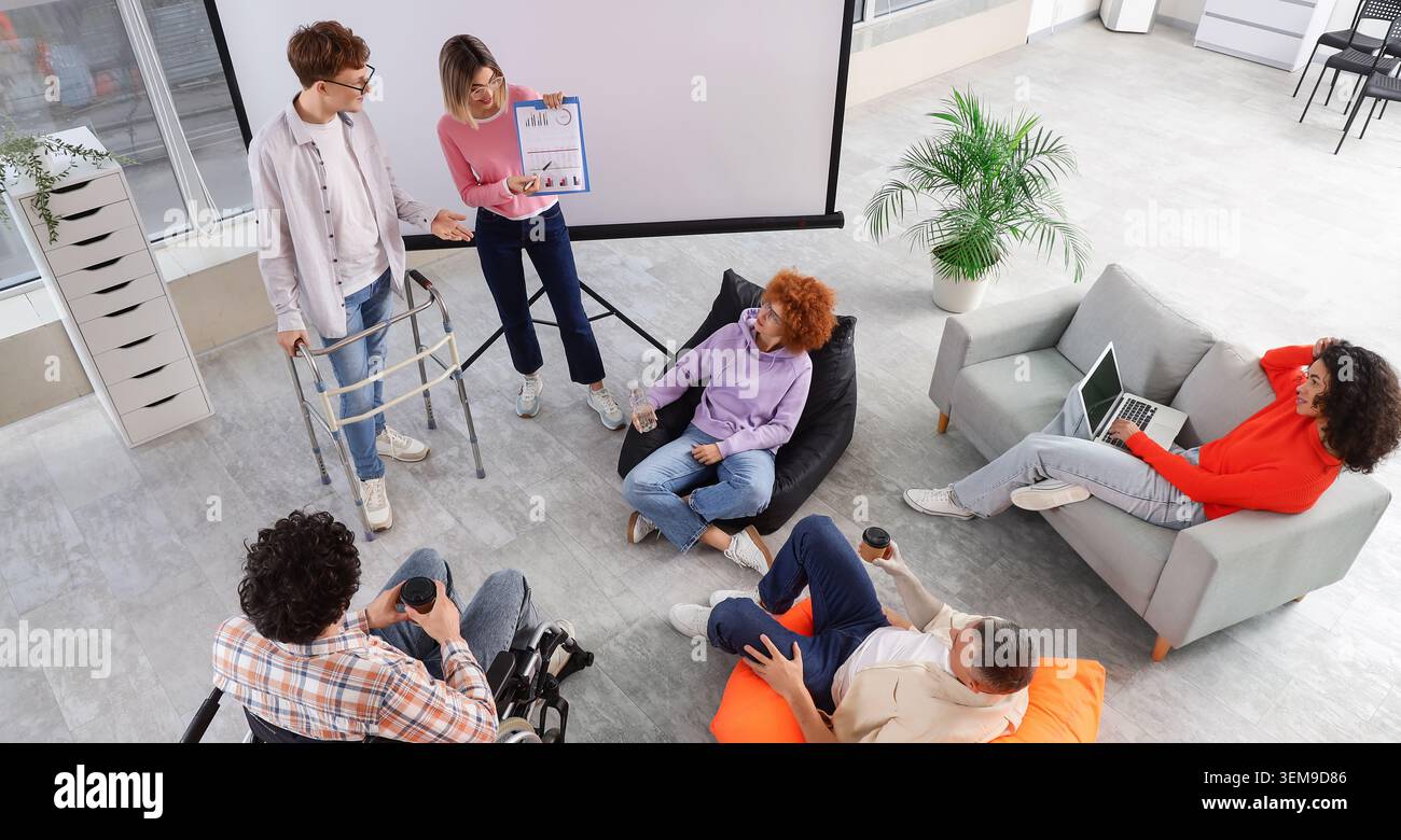 inclusive business presentation with diverse disabled coworkers in modern office, teamwork meeting, accessibility and workplace inclusion concept Stock Photo