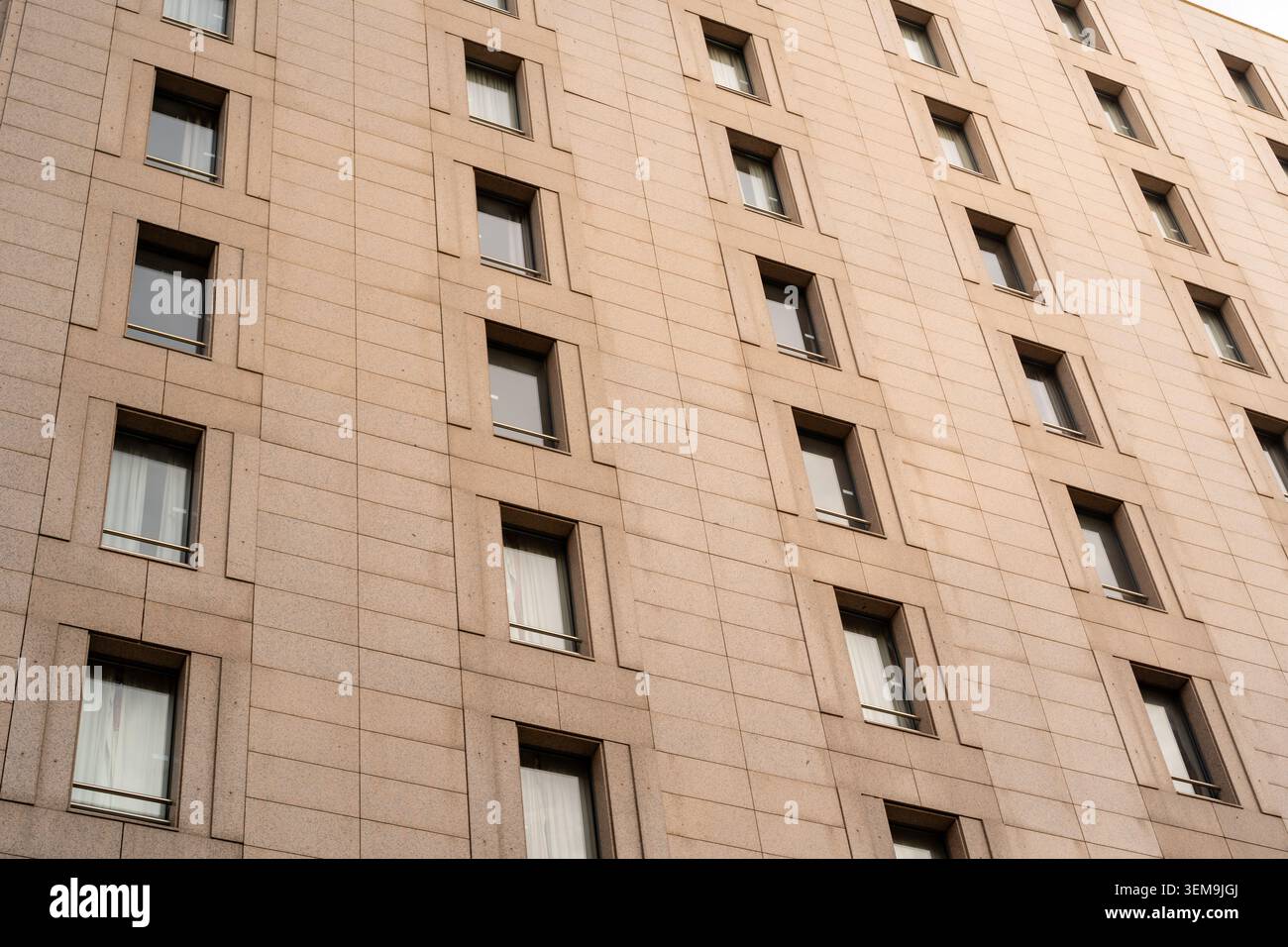 Modern building facade featuring many windows creating a symmetrical pattern Stock Photo