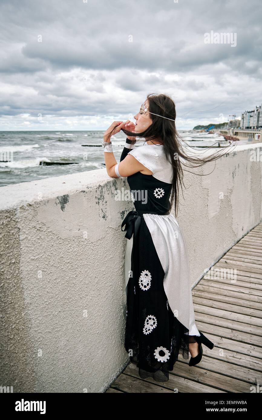 long dress blowing in wind Woman in a white dress stands on the shore. Dress flutters in wind slow motion
