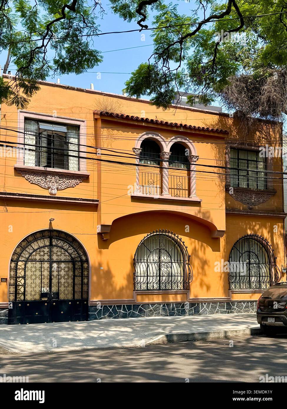 Orange residential facade with arched windows, wrought ironwork and decorative architectural details in Roma Norte, Mexico City, Mexico. - Smartphone Captured Stock Image