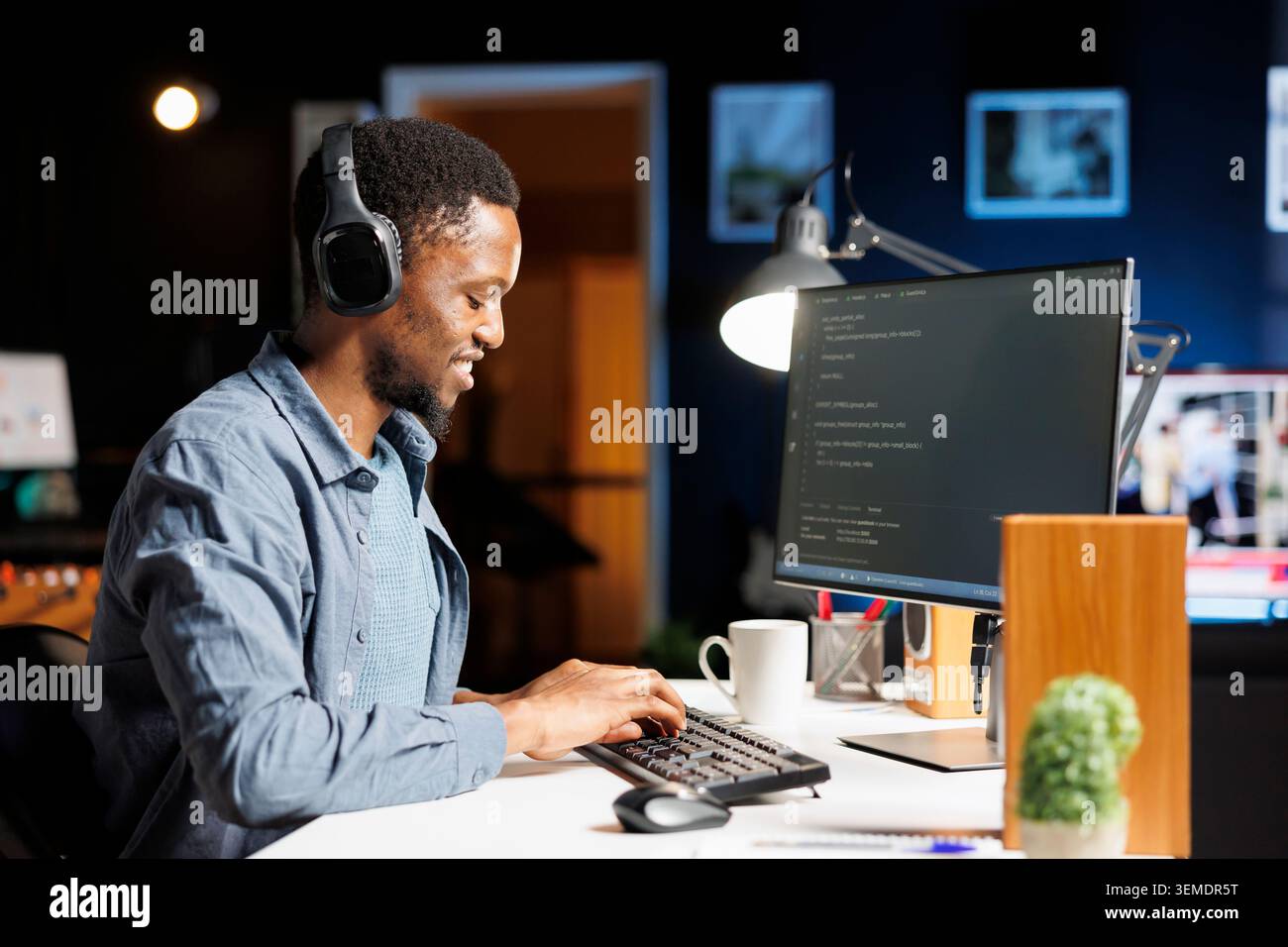 African american web developer coding server scripts on pc, using binary code and programming language on terminal window. Young system administrator debugging database security. Stock Photo