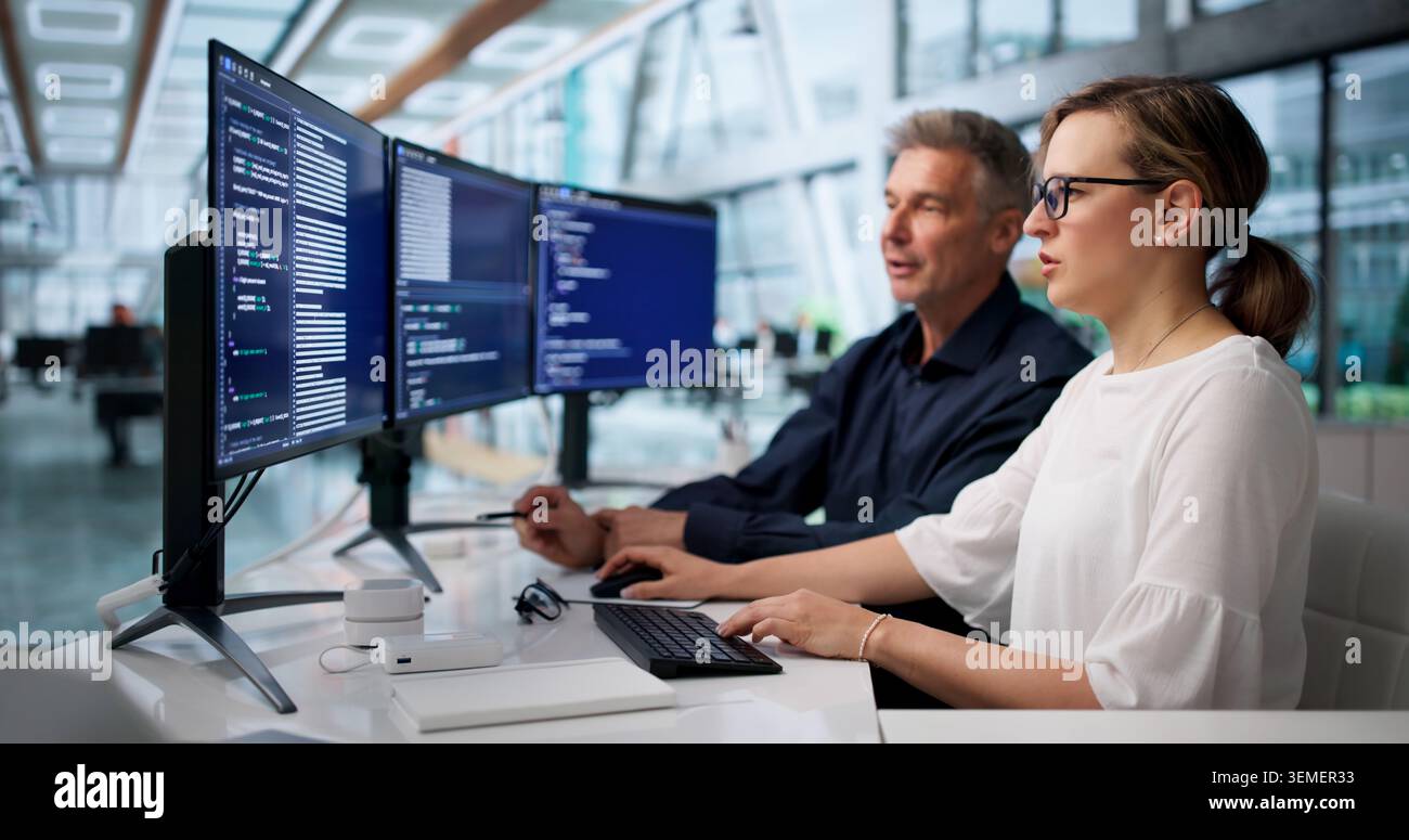 Two Software Engineers Coding Secure Systems Together In Modern Office. Stock Photo