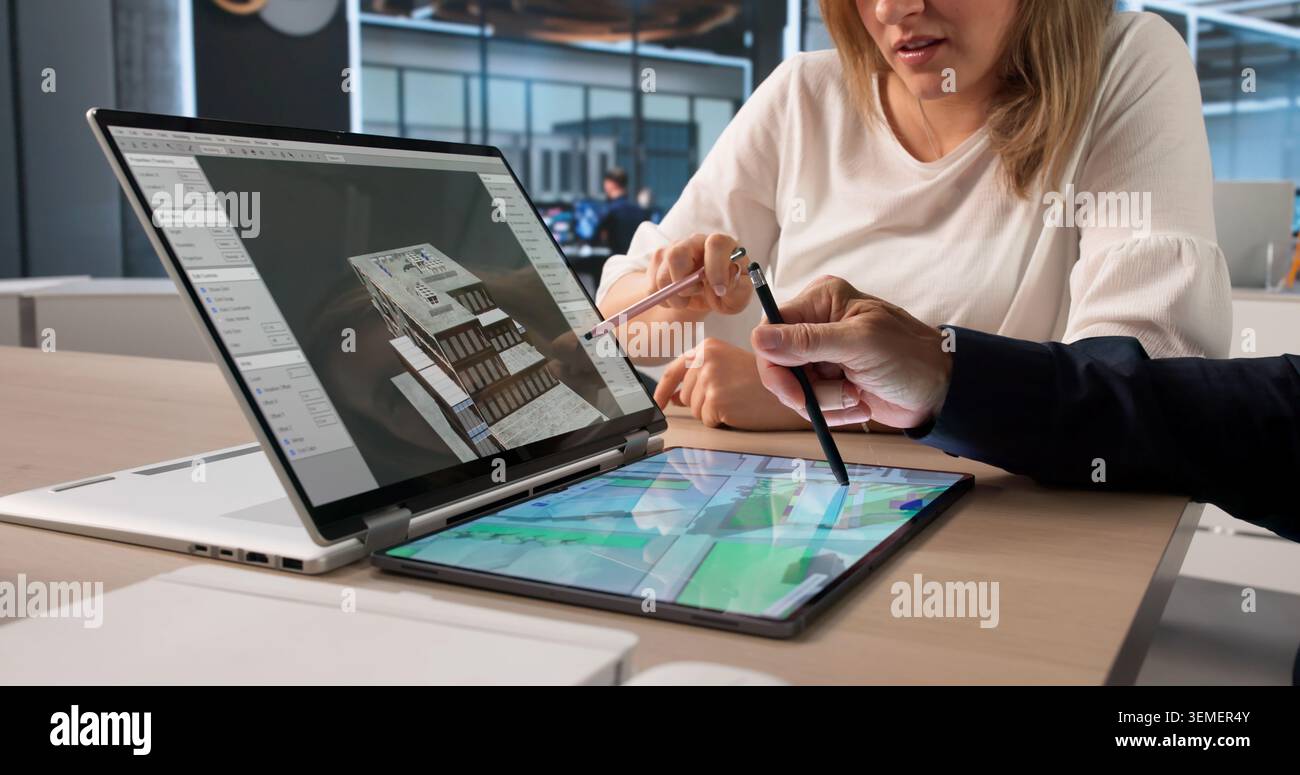 Two Architects Review 3D Building Model Together On Digital Tablet Screen. Stock Photo
