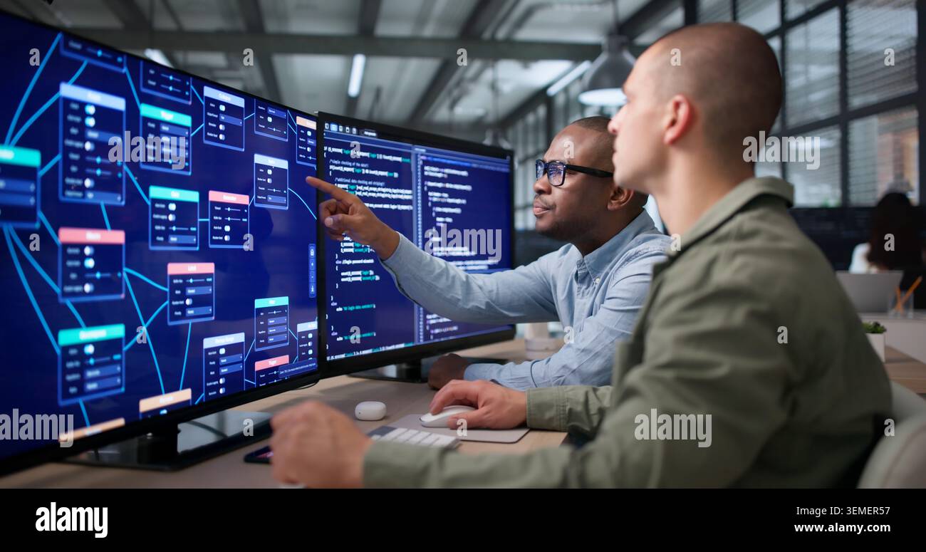 Two Young Software Developers Collaborate Using Visual Workflow Editor On Computer. Stock Photo