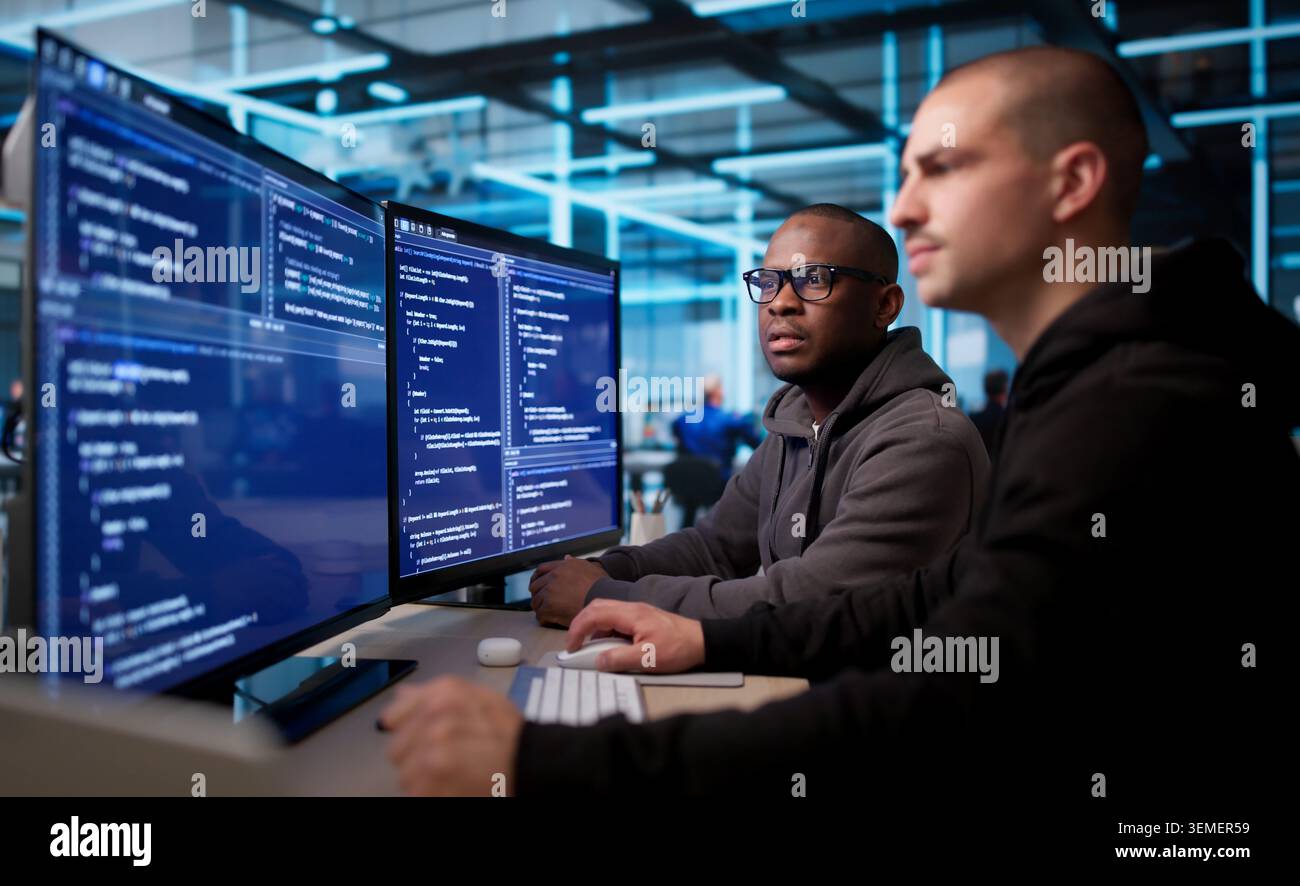 Two Software Engineers Working Together On Secure Business Application Code. Stock Photo