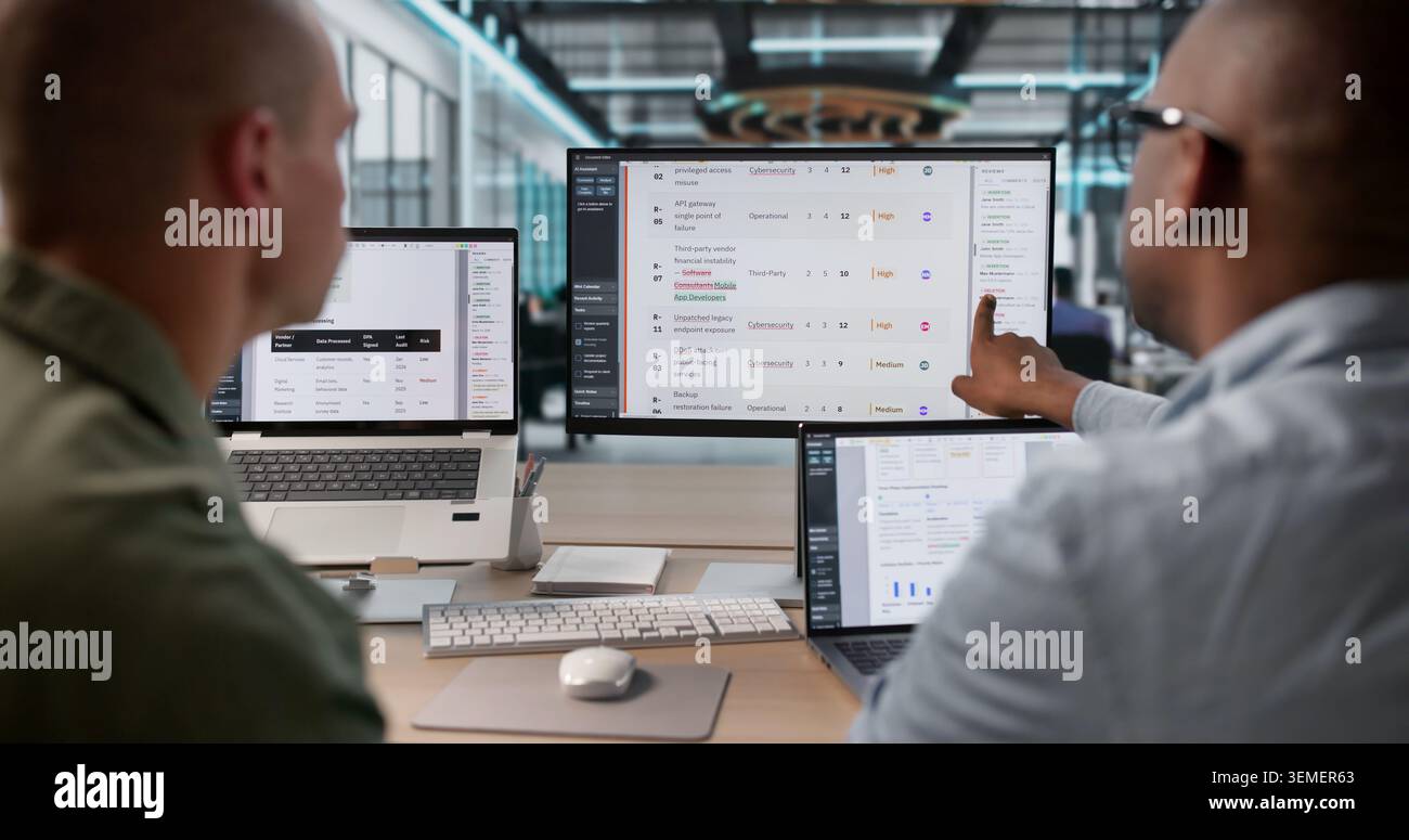 Two Risk Analysts Working Together On Detailed Financial Report Using Laptops. Stock Photo