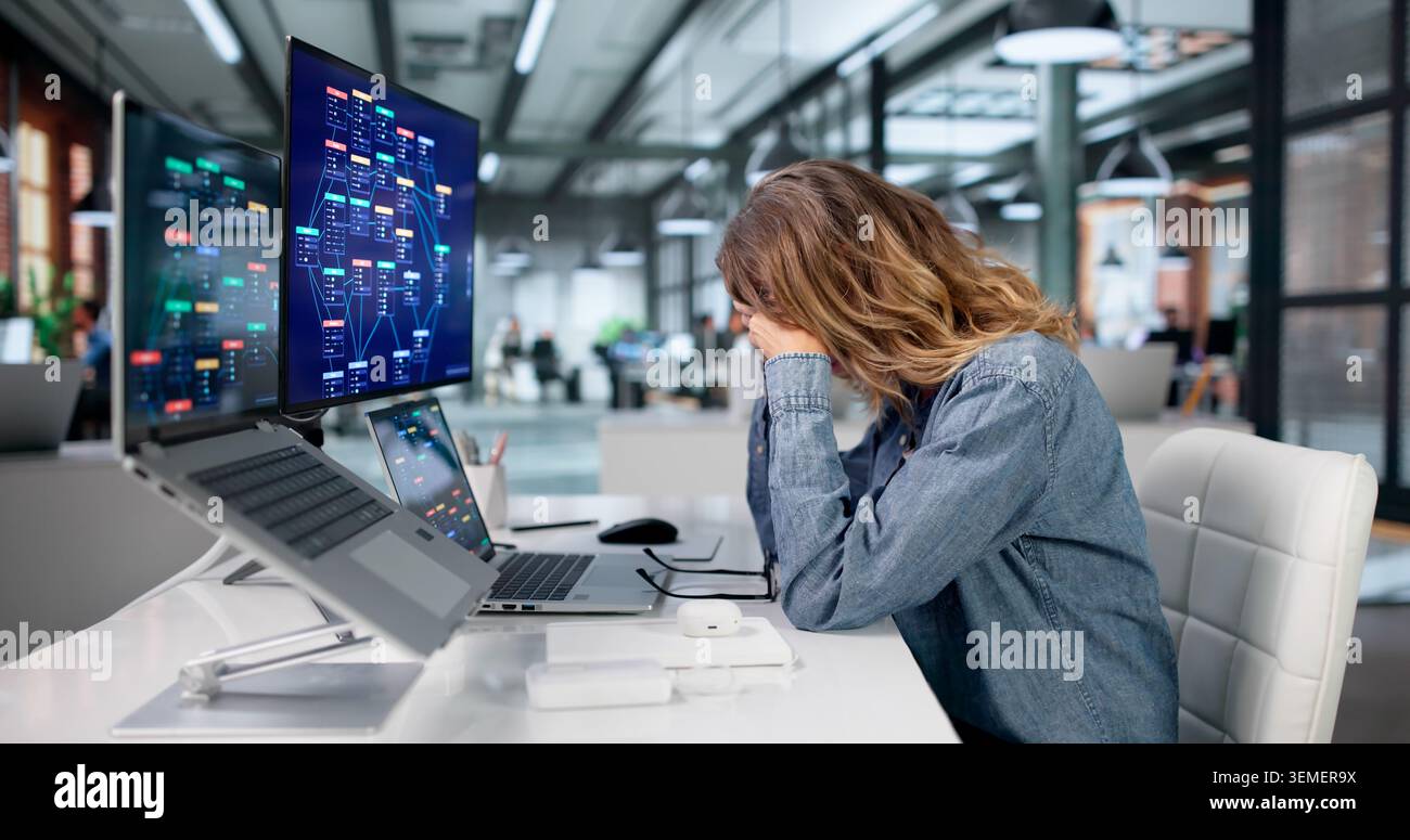 Woman Feeling Tired And Stressed While Using Low Code Platform On Laptop. Stock Photo