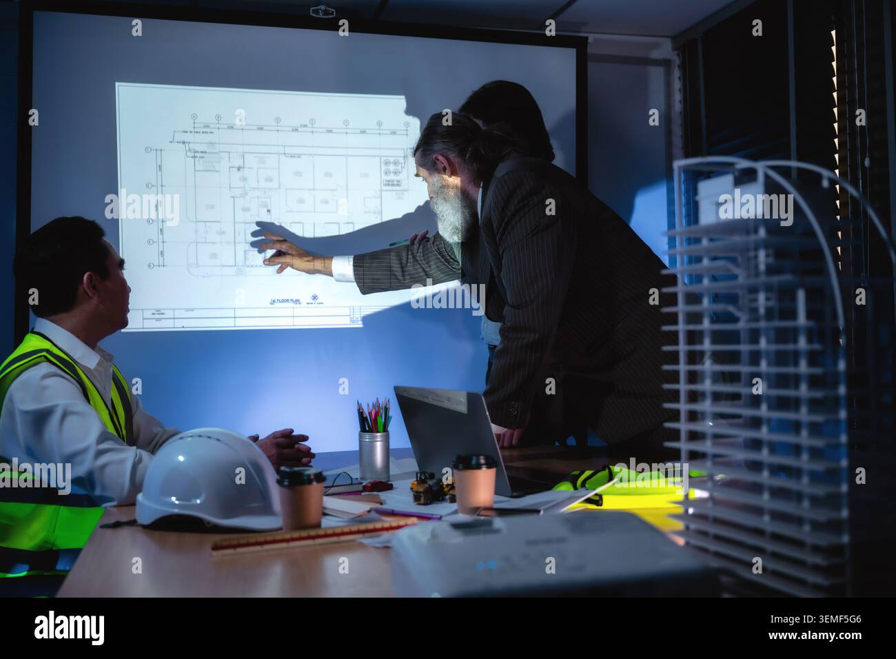 Engineering team discussing construction plan in dark meeting room, Construction manager explaining infrastructure plan with senior manager brainstorm Stock Photo