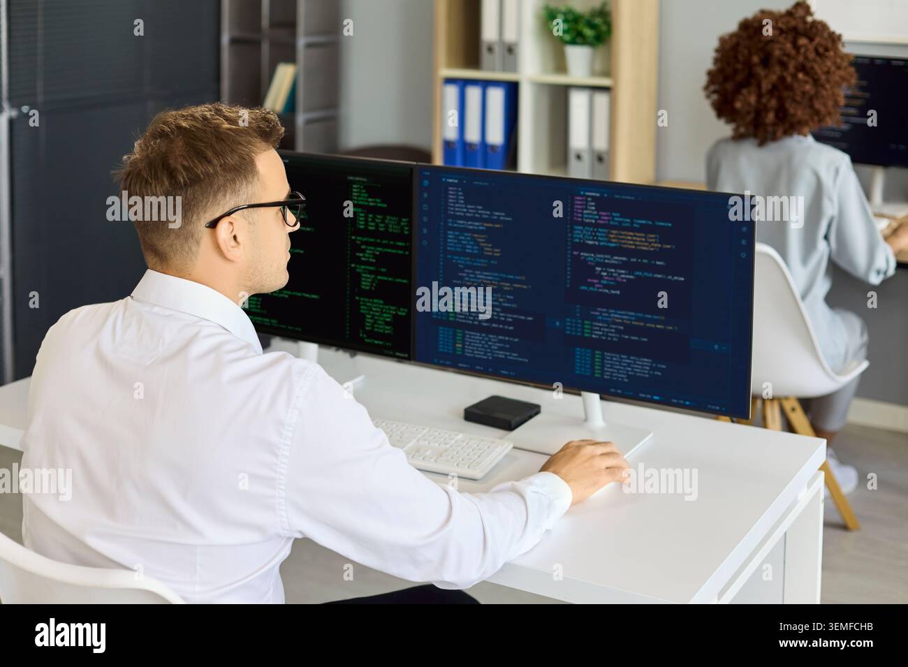 Programmer coding on wide monitor in office, focused software workflow engineering Stock Photo