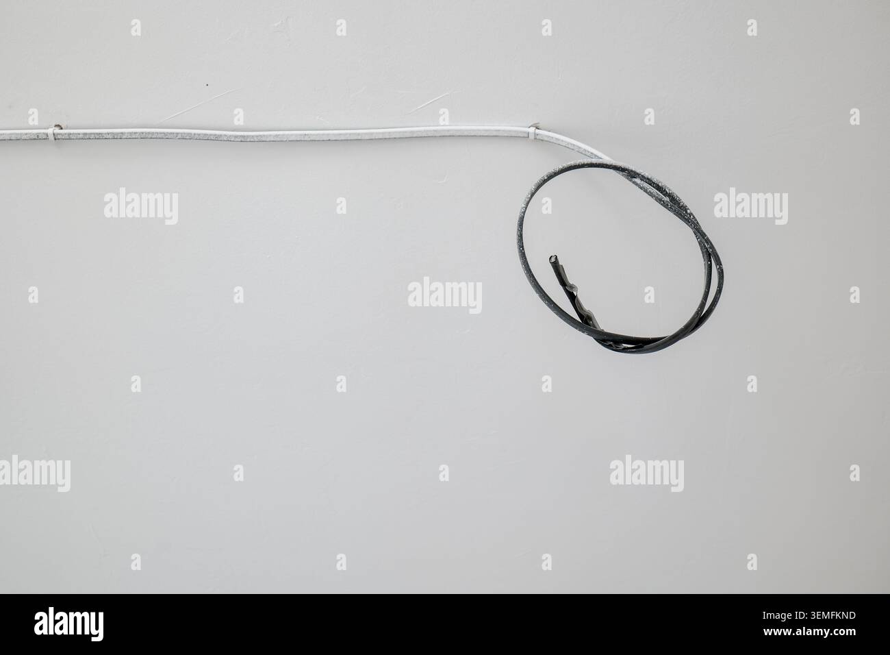 White and black electrical wires on a white wall Stock Photo