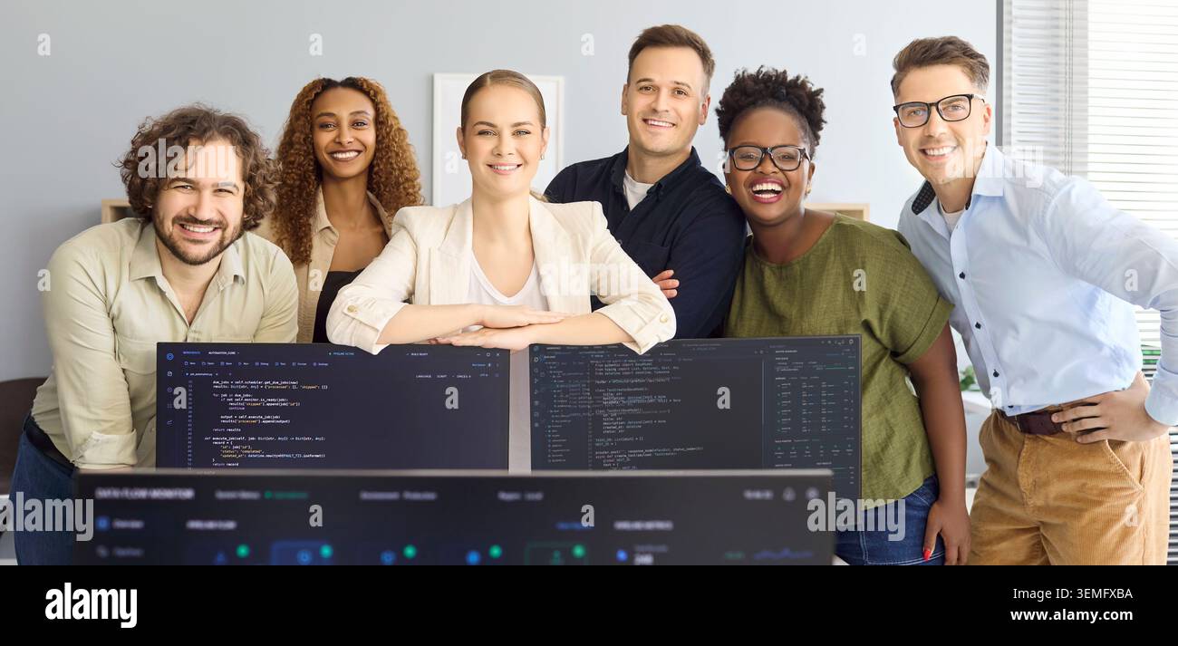 Happy software developers team portrait in startup office behind coding monitors Stock Photo