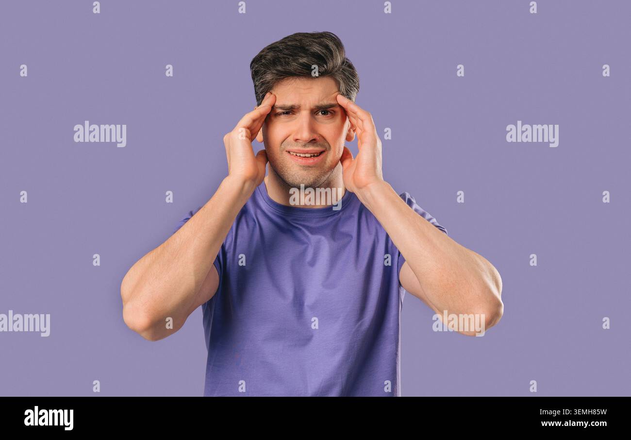 30s aged man having headache, touching temples, Suffering on violet background. Stock Photo