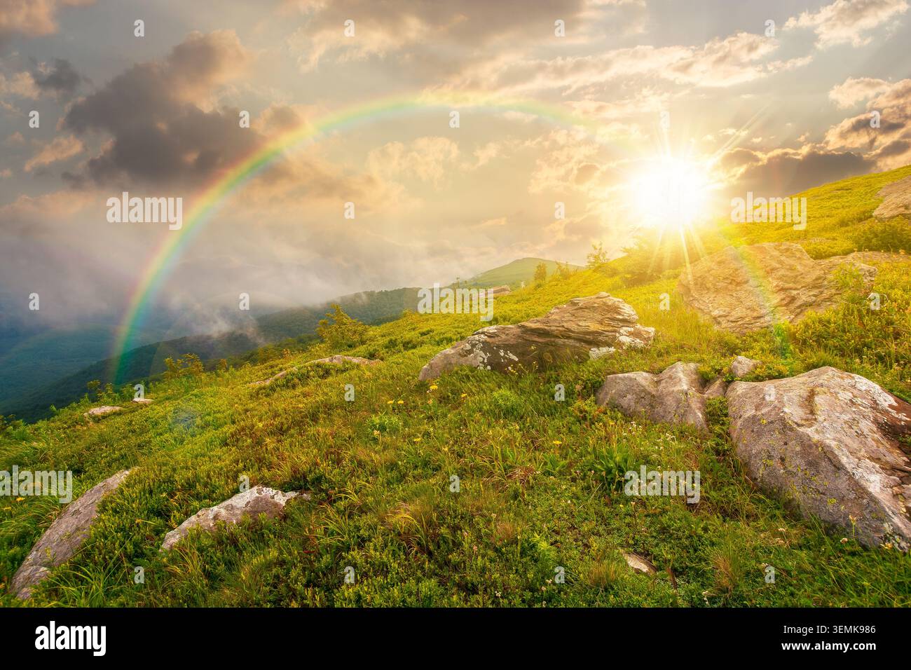 sunset over green landscape of mountain in summer. view of rock among grass on the hillside. travel background under a cloudy sky. mountain scenery wi Stock Photo
