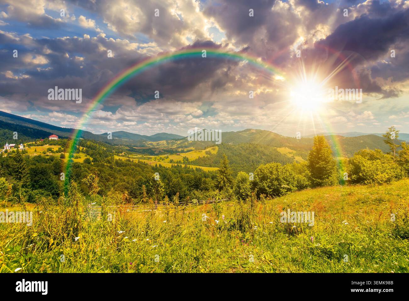sunset over agricultural field on hillside in mountains near village. carpathian mountain landscape in summer. countryside view of alpine fields and r Stock Photo
