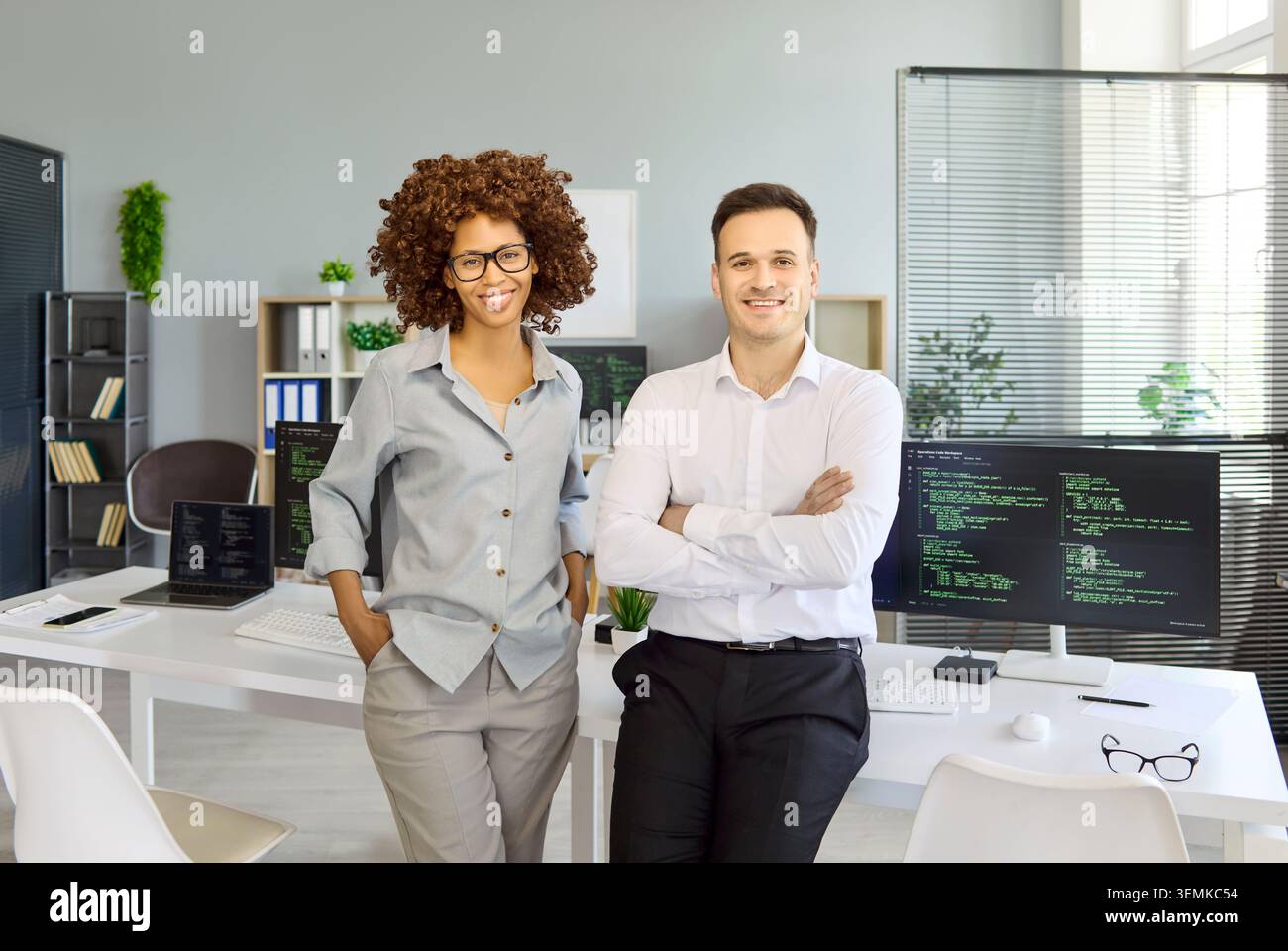 Smiling programmers and developers in modern office, teamwork with coding monitors Stock Photo