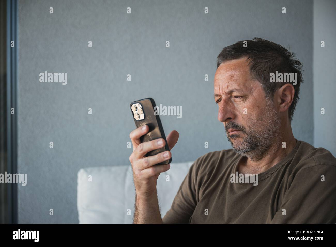 Middle-aged man looking at smartphone with serious expression, selective focus Stock Photo