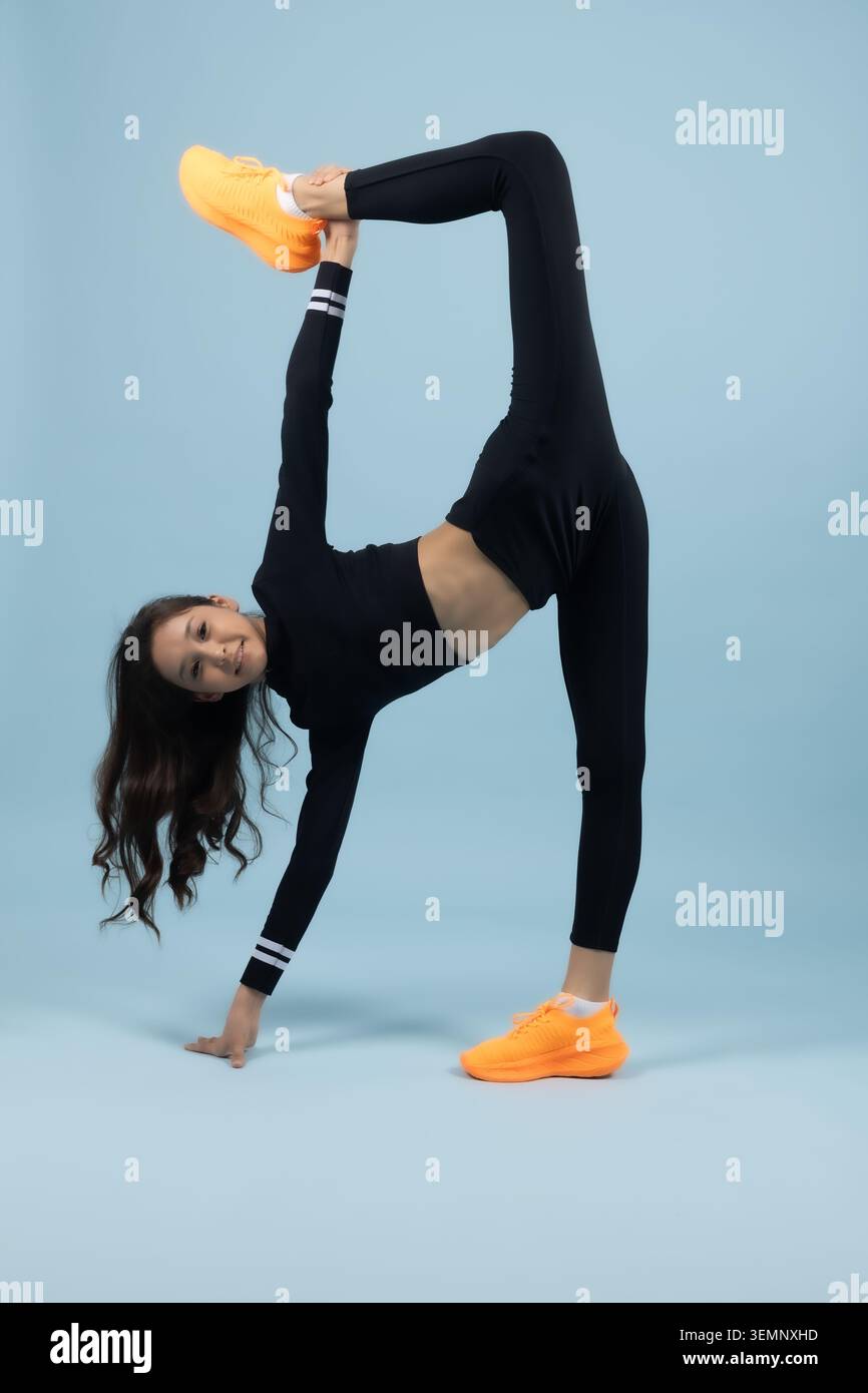 Amazing young woman practicing advanced yoga leg vertical split pose Stock Photo