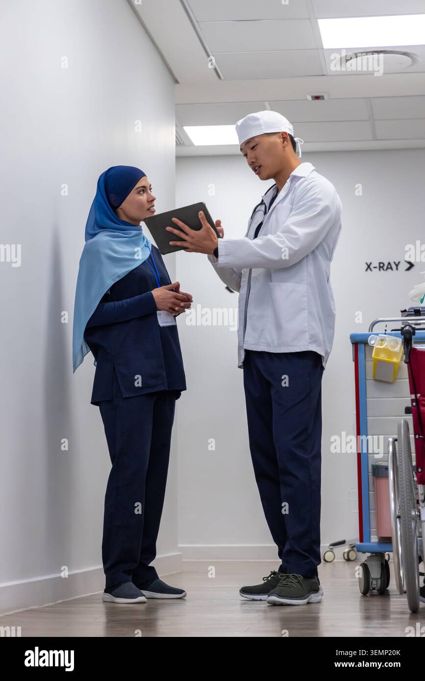 Diverse medical colleagues in navy scrubs and white coat discussing scan on tablet near X-RAY sign Stock Photo