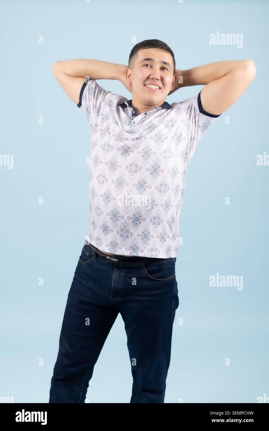 Young man holding hands behind head yawning or stretching relaxedly Stock Photo