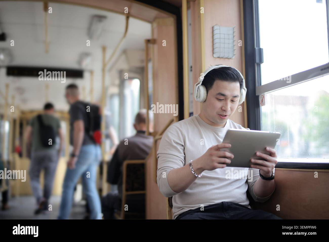 Young Asian man using a tablet on public transit Stock Photo