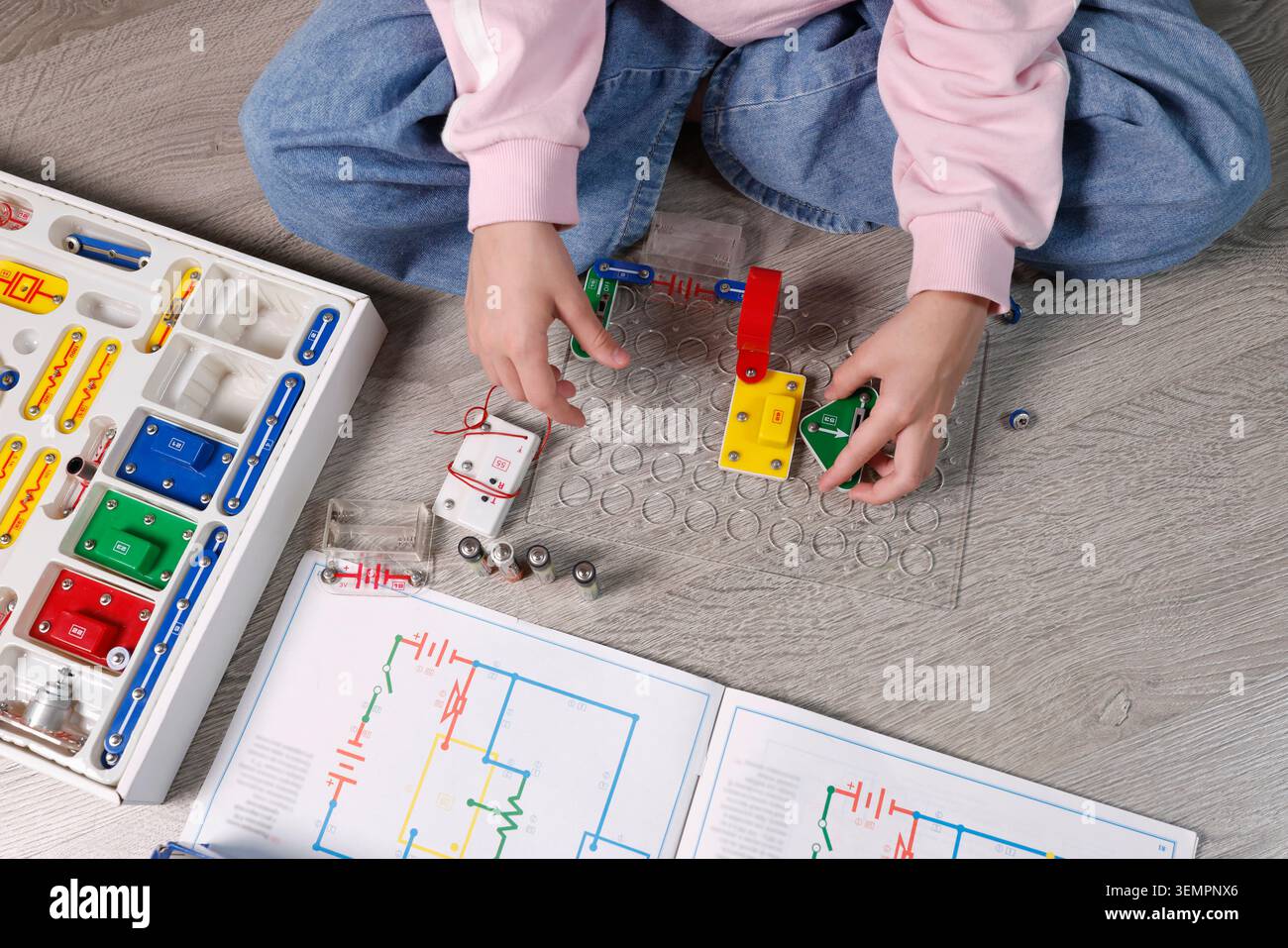 Child hands close-up assembling electronic circuit components on plastic grid base plate. Educational STEM laboratory activity for physics science Stock Photo