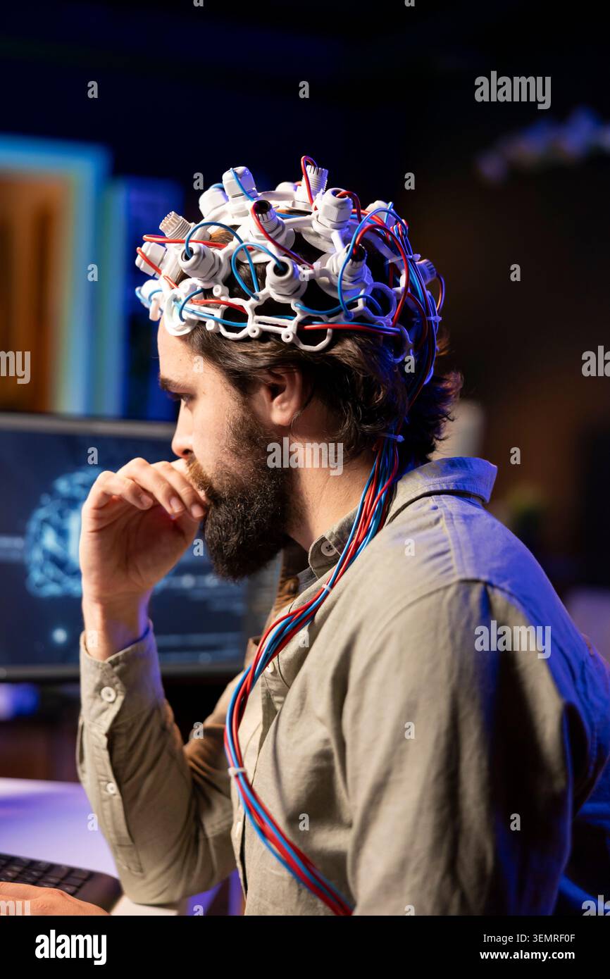 IT admin coding and using EEG headset to upload brain into computer, gaining immortality, neuroscientist engineering transhumanism experiment, inserting consciousness into cyberspace. Stock Photo