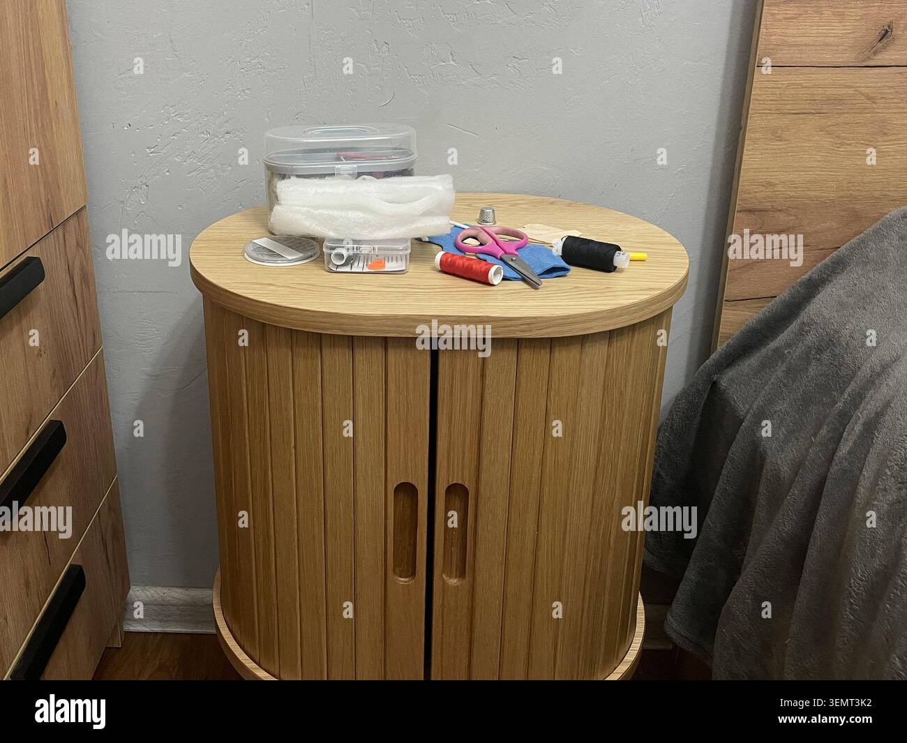 A tailor's sewing kit on a table. Needles, thread, and fabric for sewing. Stock Photo
