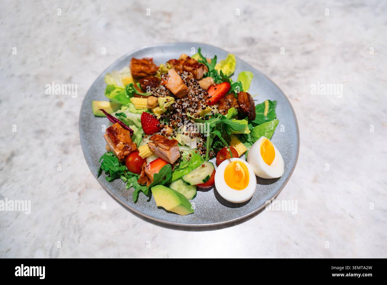 Fresh healthy salad with grilled chicken, quinoa, avocado, strawberries, and soft-boiled eggs on a Stock Photo