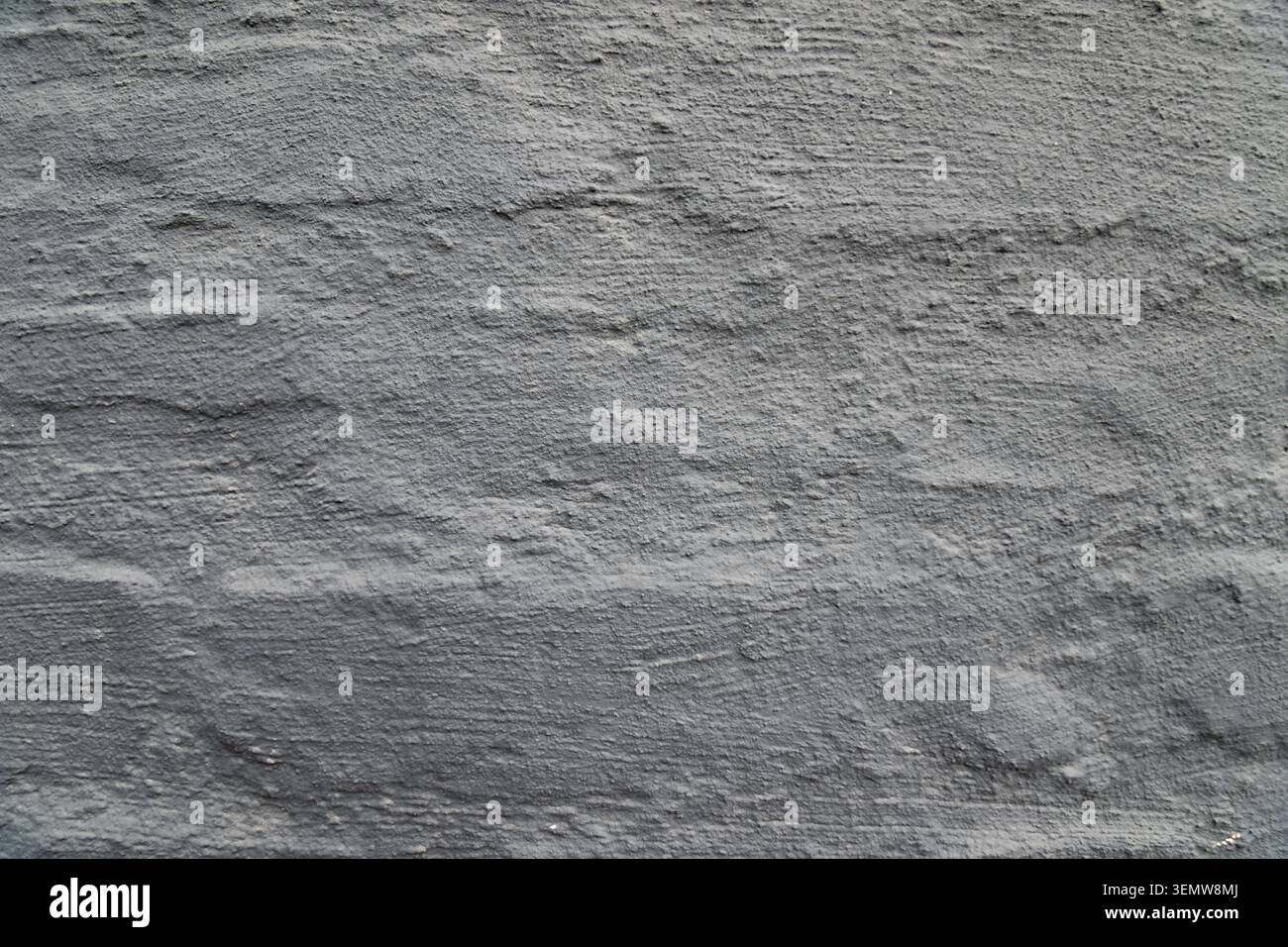 Roughly applied dark gray stucco layer on an outdoor masonry wall structures providing an abstract textured background option for digital artwork Stock Photo