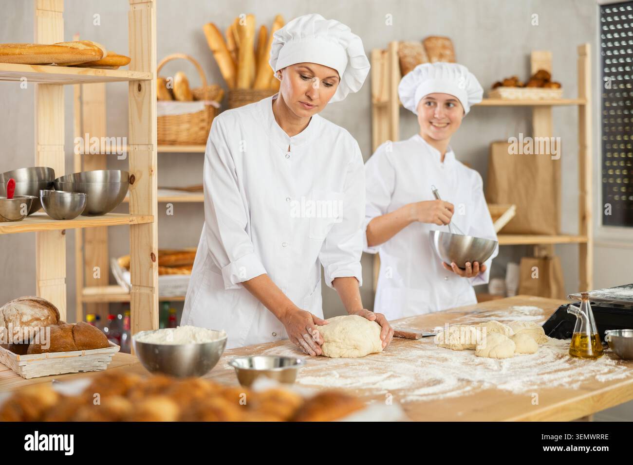 Female bakers in uniform preparing gray dough Stock Photo