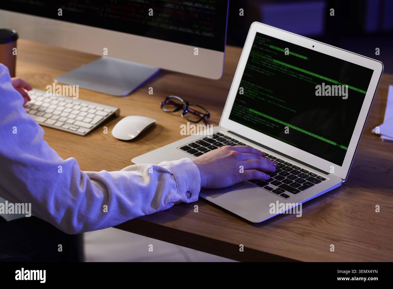 Female programmer working with computer and laptop in office at night Stock Photo