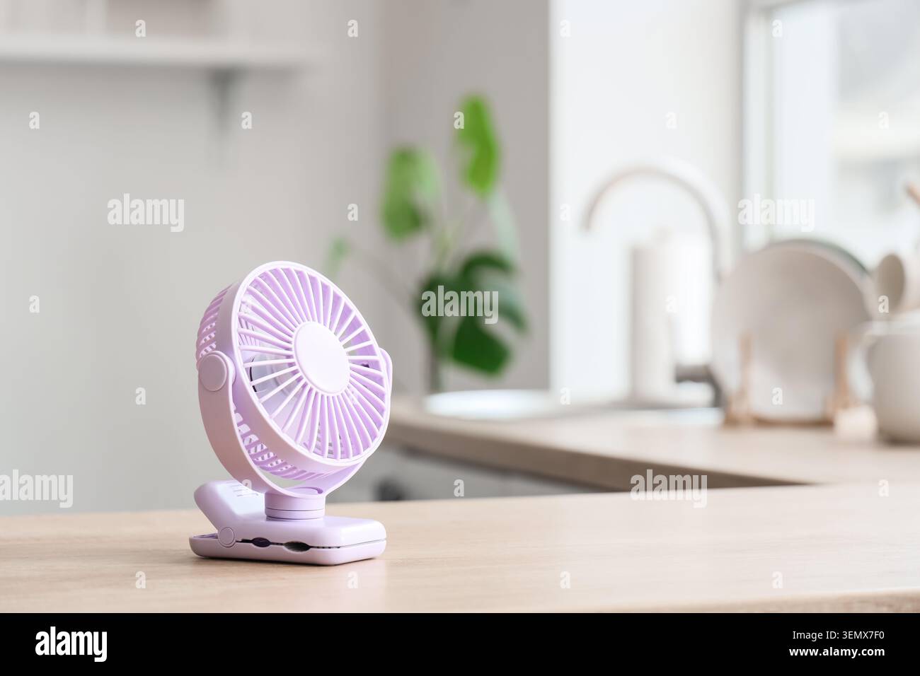 Lilac mini fan on table in kitchen, closeup Stock Photo