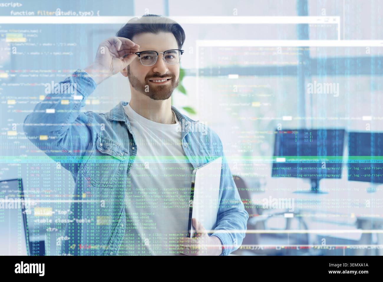 Smiling male software developer with glasses and laptop, programming code overlay, digital technology and innovation Stock Photo