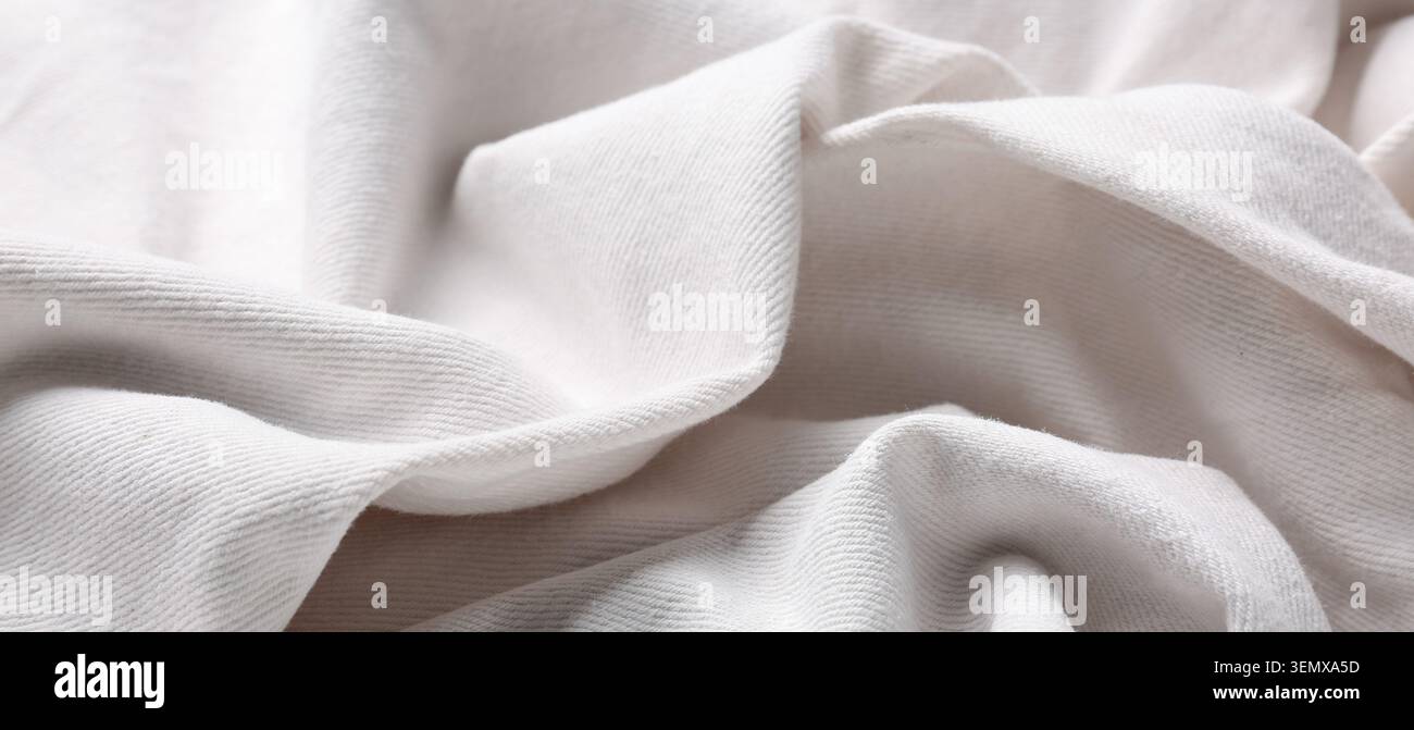 Soft white cotton fabric texture background with gentle folds and wrinkles, close-up view of natural textile material Stock Photo