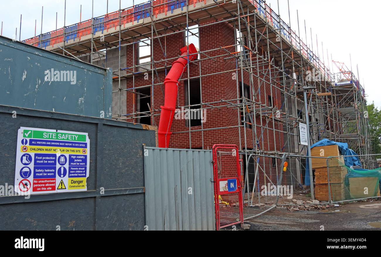 Building site with scaffolding and red construction chute in Hindley, Wigan, Greater Manchester, England, UK. Stock Photo