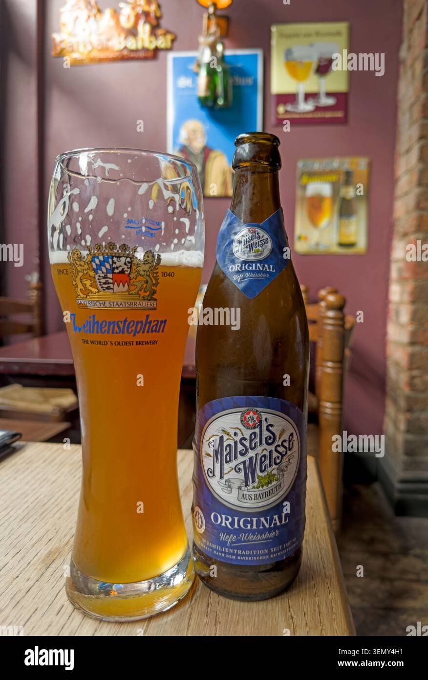 A bottle and branded glass of Maisel’s Weisse Original wheat beer on a table inside the Belgian Bar in Altrincham, Trafford, Greater Manchester Stock Photo