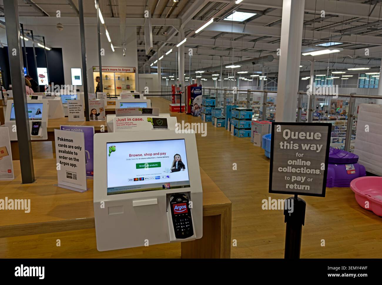 Argos self-service catalogue ordering point inside Sainsbury's Leigh store, Greater Manchester, with online collection queue sign. Stock Photo