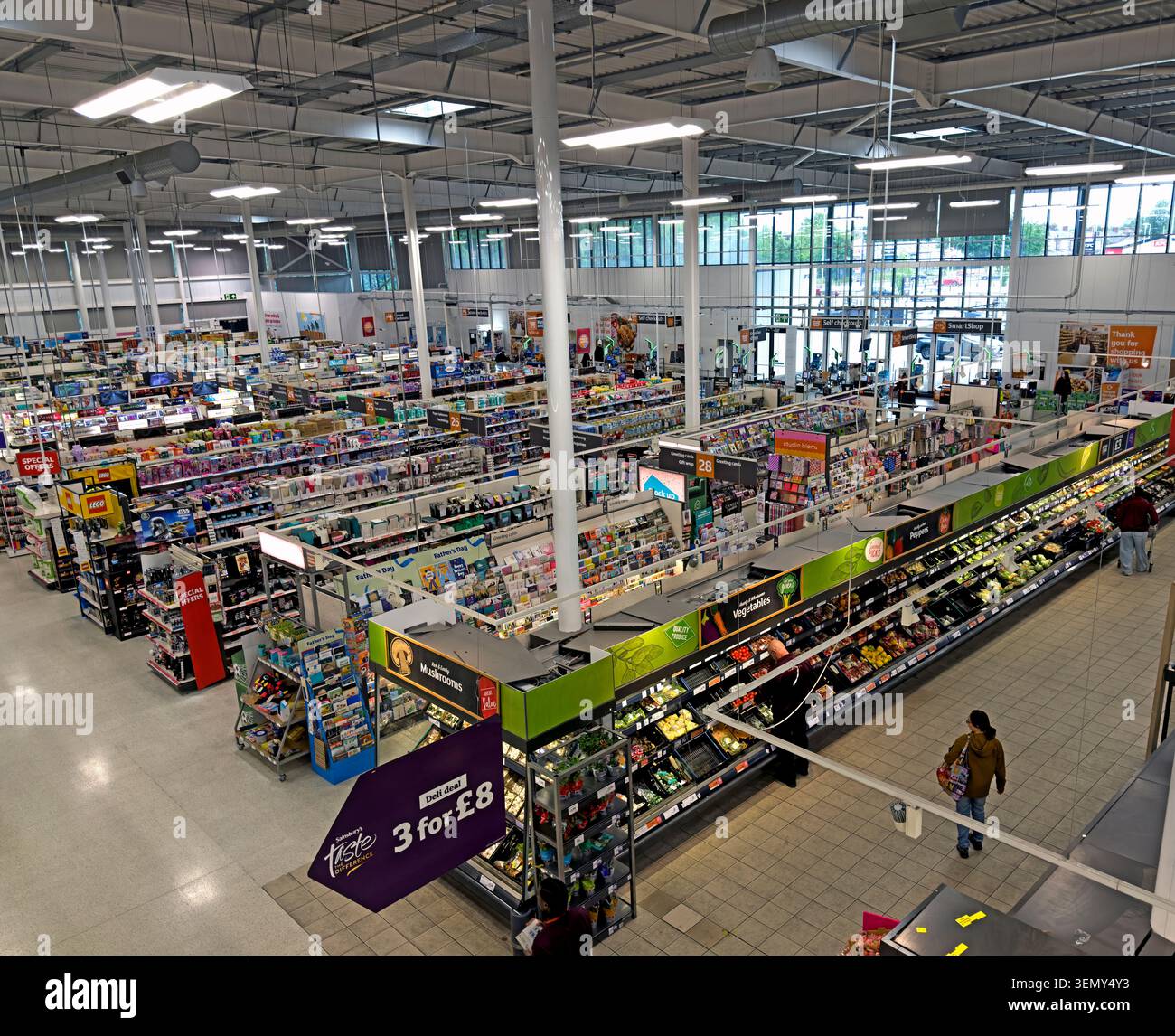 Panoramic interior of Sainsbury’s superstore in Leigh, Greater Manchester, looking over & showing grocery aisles, shoppers and retail displays. Stock Photo
