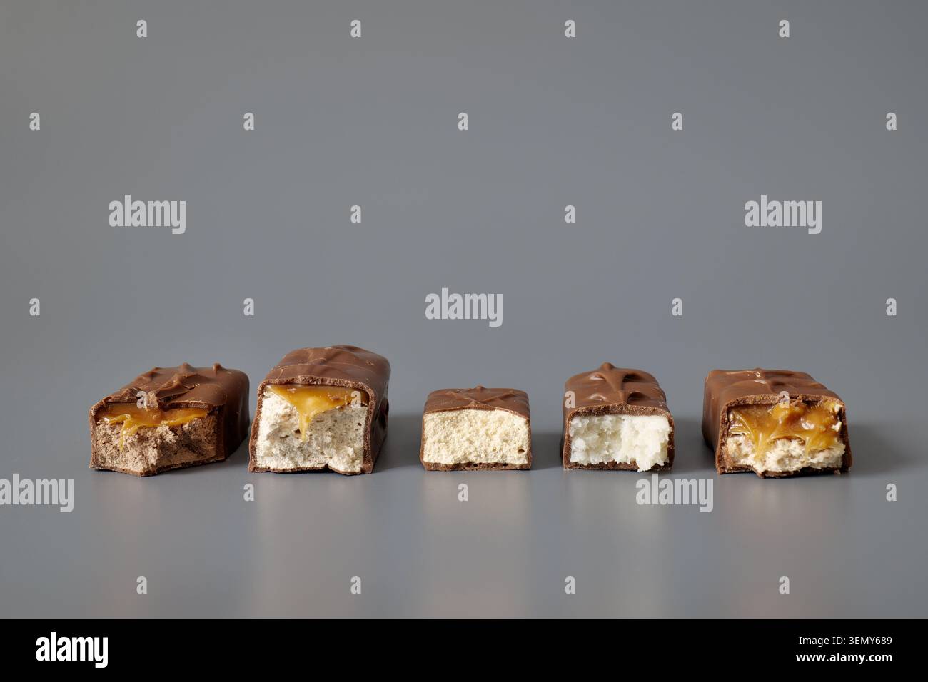 Five broken chocolate bars with assorted fillings on a gray background Stock Photo