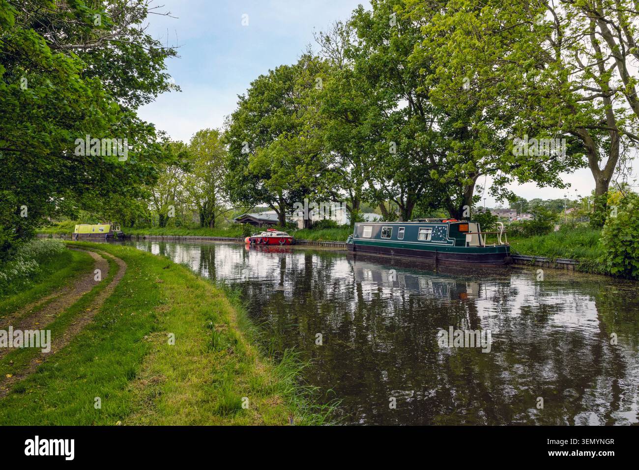 Tranquil waters and moored narrowboats on the historic Lancaster Canal at Galgate in Lancashire, North West England. Stock Photo