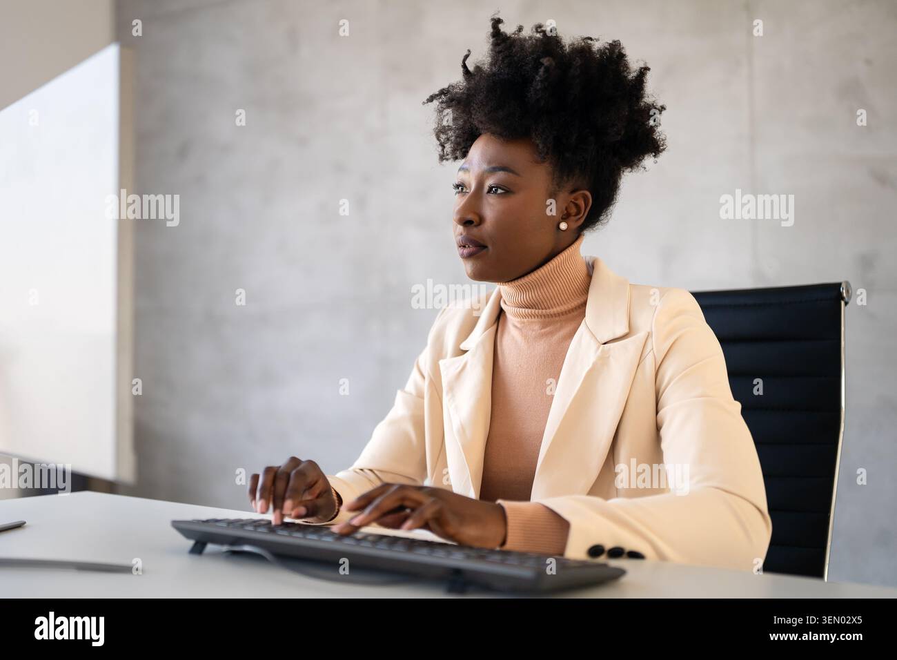 Young successful business woman using a computer while working in a startup company office Stock Photo