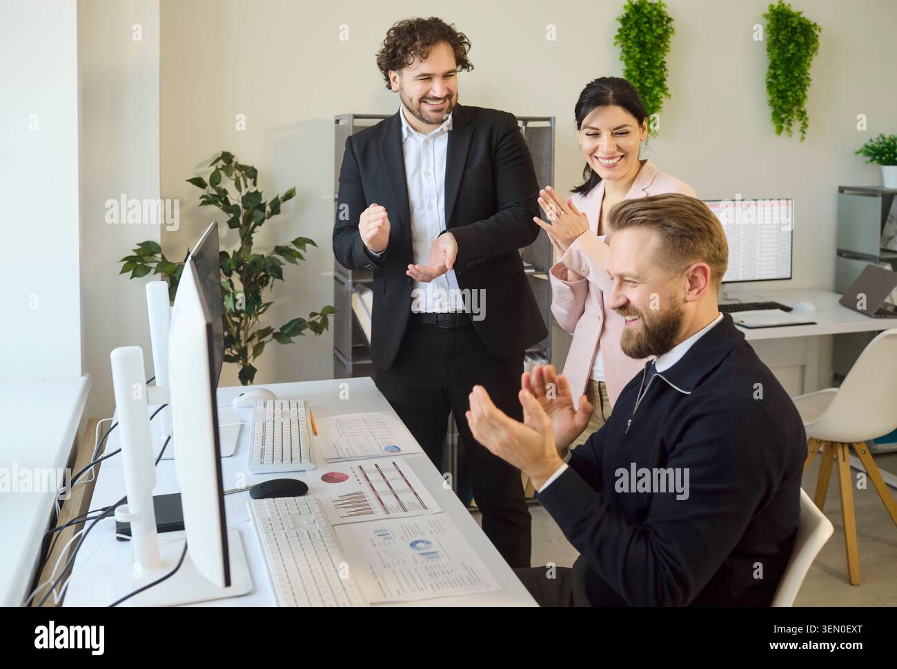 Happy colleagues celebrating achievement after successful office analytics results Stock Photo