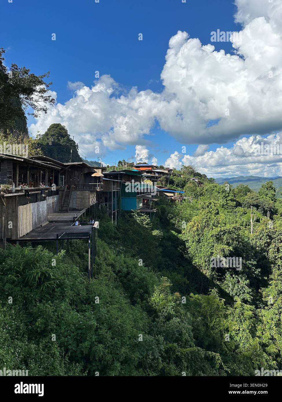 Living on the edge: wooden stilt houses cling to a lush mountainside near Mae Surin National Park, Thailand - Smartphone Captured Stock Image