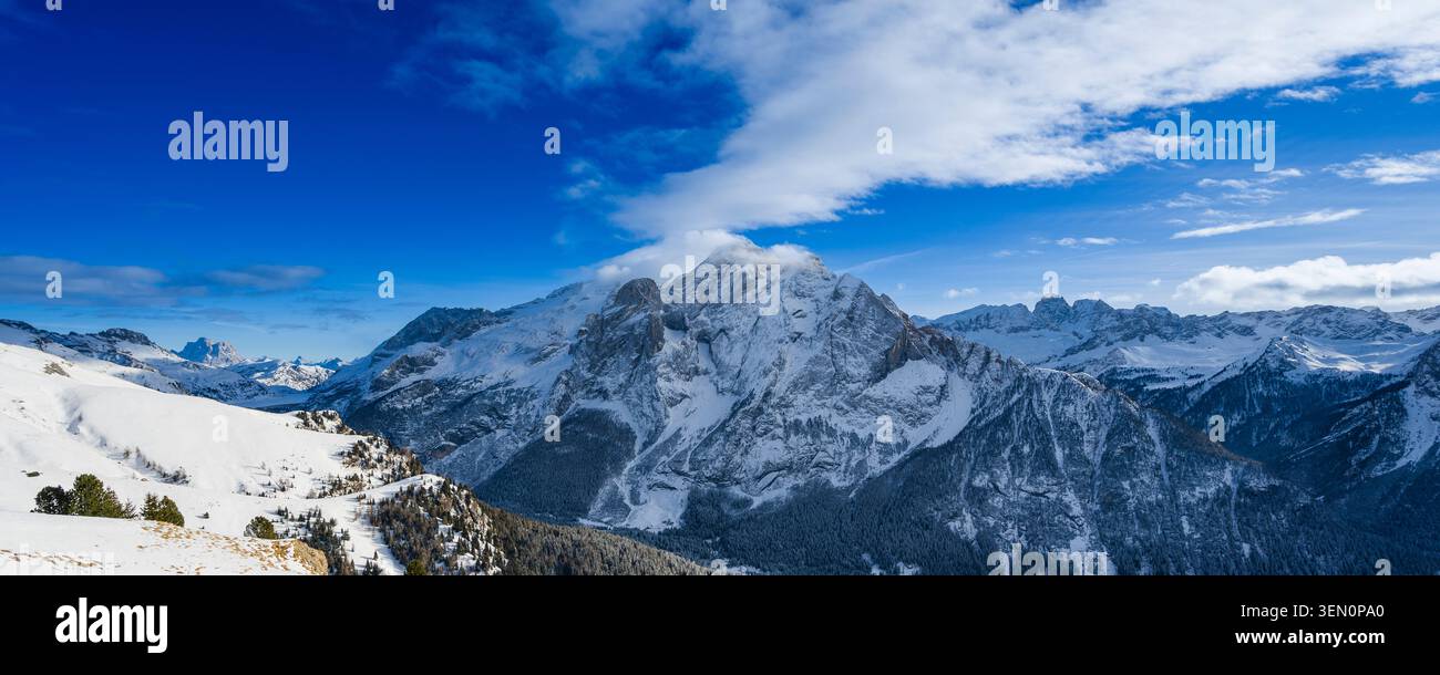 Snow-covered mountain range under a bright blue sky with scattered clouds. Stock Photo