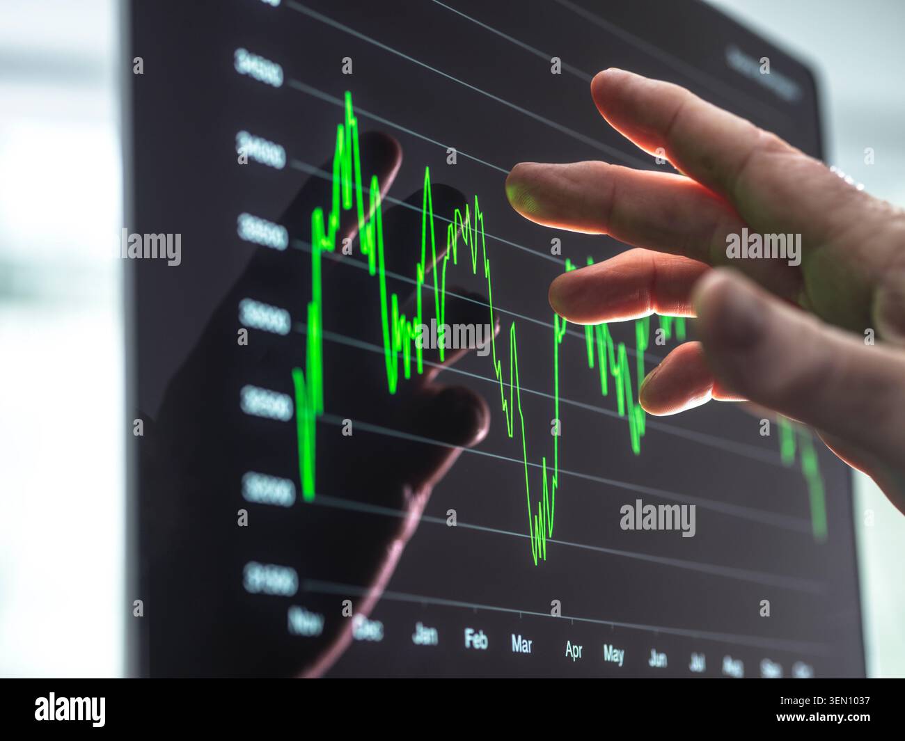 Hand touching digital graph on a screen showing fluctuating financial data. Stock Photo