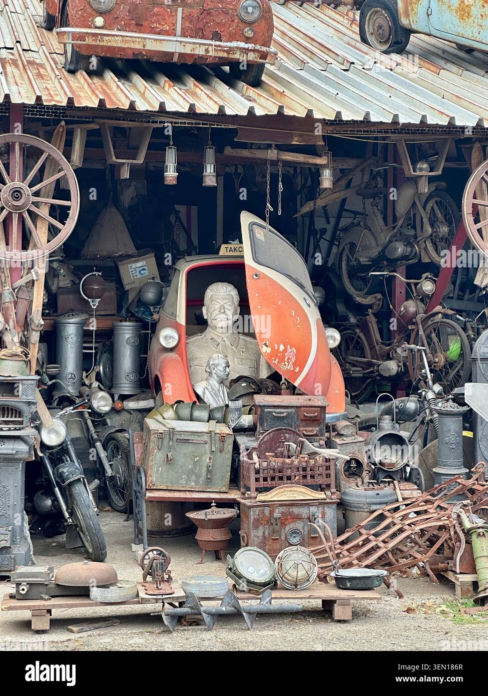 Stalin in the Workshop, A vintage scooter peeks from a wonderfully crowded workshop packed with wheels, tools and mechanical relics. - Smartphone Captured Stock Image