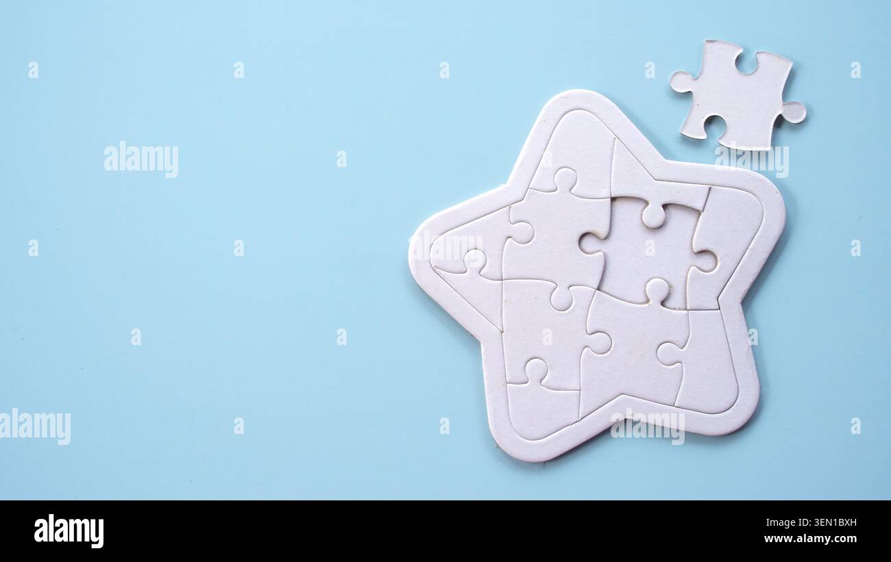 A white star-shaped jigsaw puzzle with one piece missing, set against a soft light blue background. Stock Photo