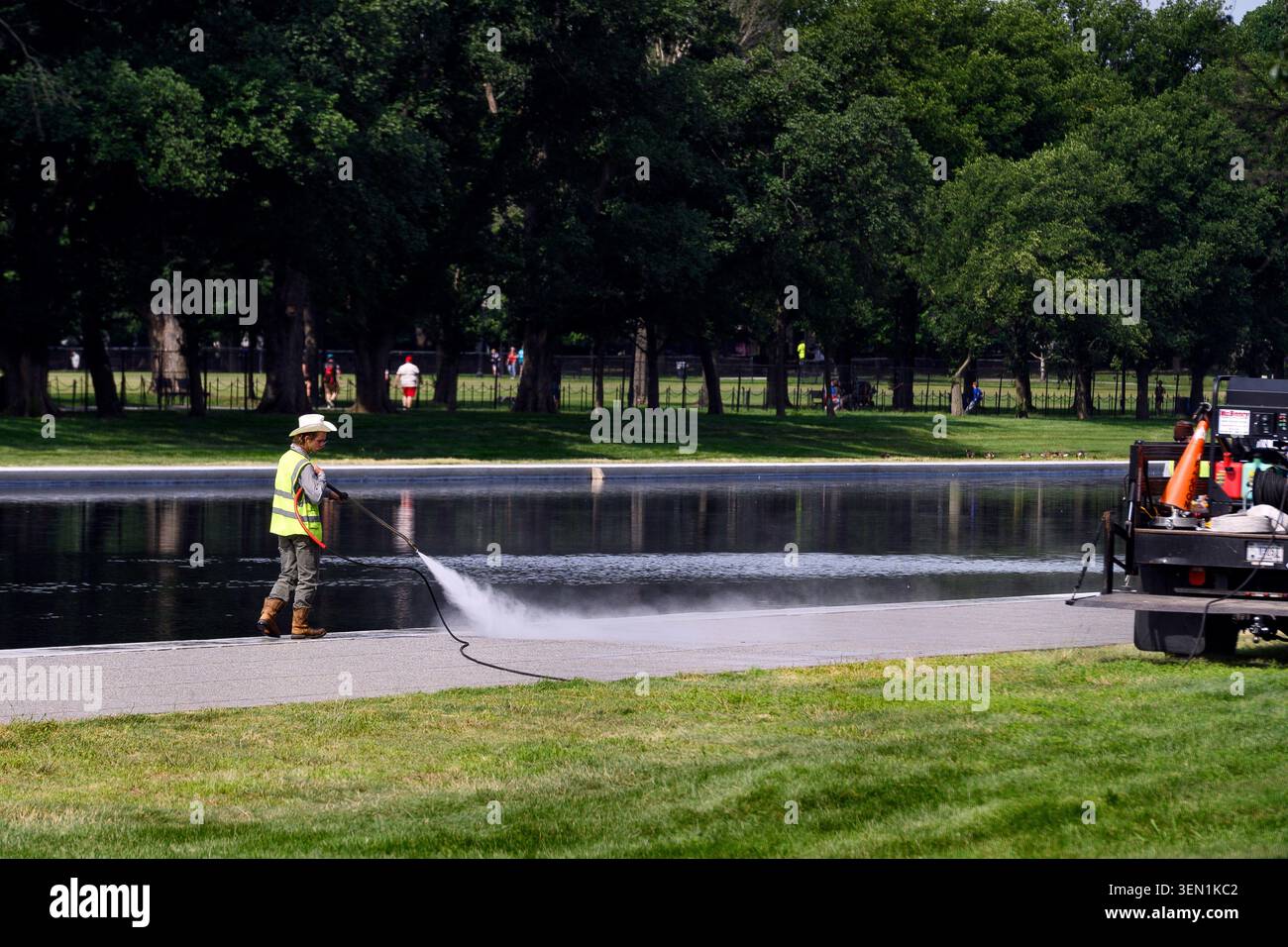 A worker power washes the walkway adjacent to the Reflecting Pool in ...
