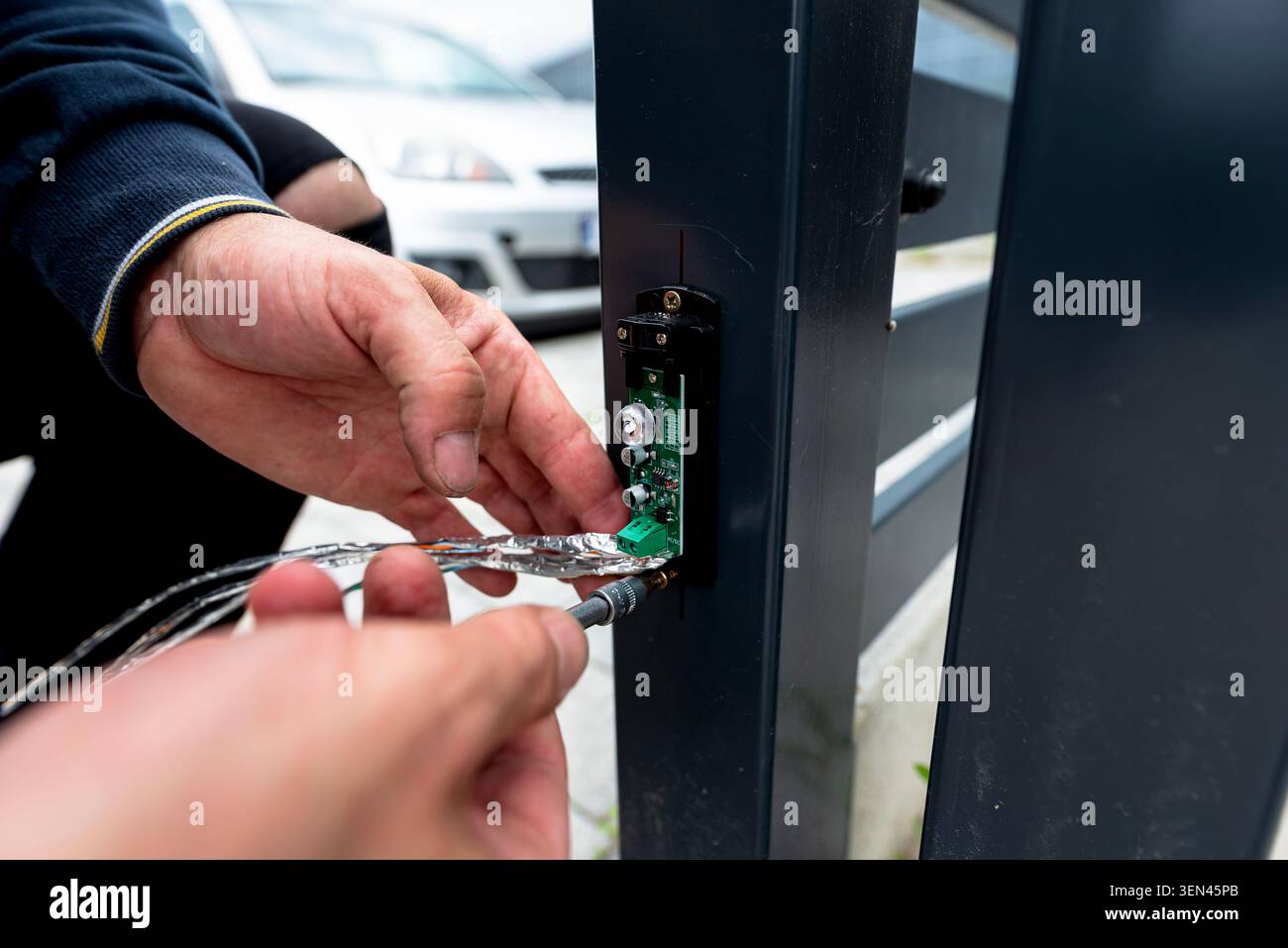Hand connecting network cable to safety sensor on automatic gate frame Stock Photo